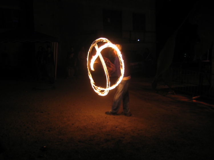 Un ragazzo vicino al palco inizia a giocare con le torce di fuoco, facendole girare in cerchio.