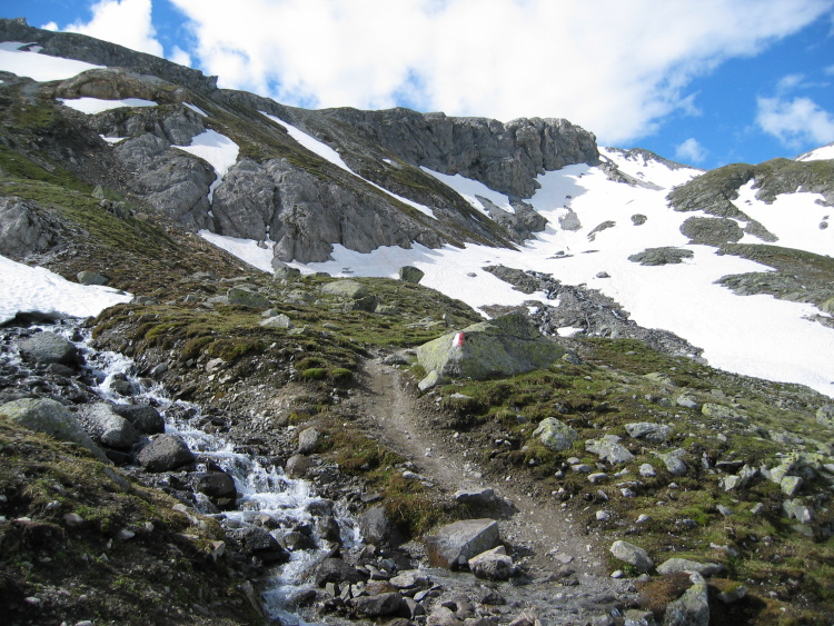 Il sentiero di lì a poco passa per nevai e ruscelli, salendo fino in cima.
