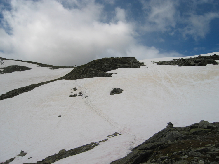 Nella neve si vedono le impronte del sentiero battuto, in cima i paletti d'indicazione sulla forcella.